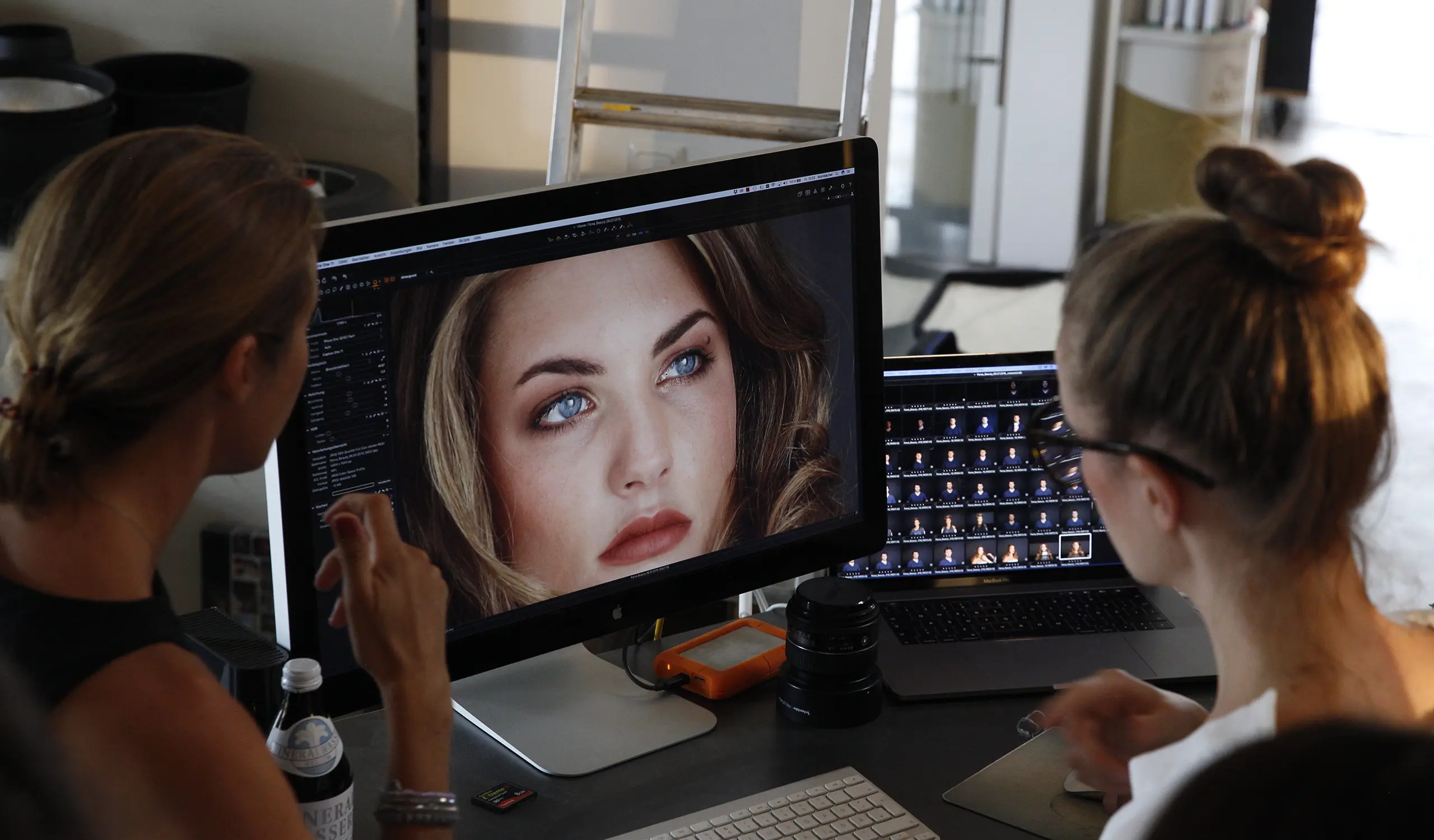 Zwei Frauen schauen sich Bilder eines Fotoshootings an.